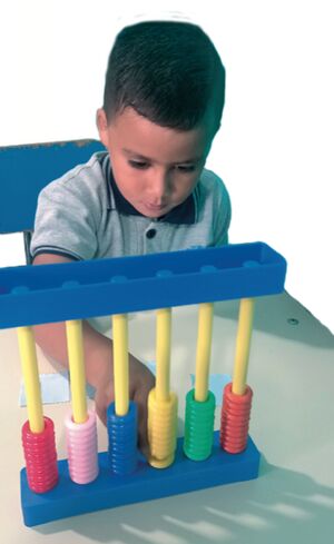 Niño preescolar juega con ábaco.